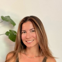 Selin, smiling, seated on her mat in a bright studio.